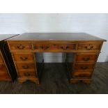A reproduction yew wood twin pedestal desk fitted nine drawers with green leather top,