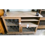 A light oak TV stand with shelves and leaded light doors under,