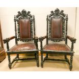 A pair of Victorian heavy carved dark oak elbow chairs with Rexine upholstered seats and backs
