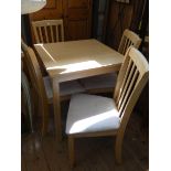A light oak finished square kitchen or dining table with four matching slat back chairs with cream