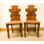 A pair of Victorian oak hall chairs with decorative backs