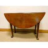 A Georgian circular oak drop leaf dining table standing on pad feet,