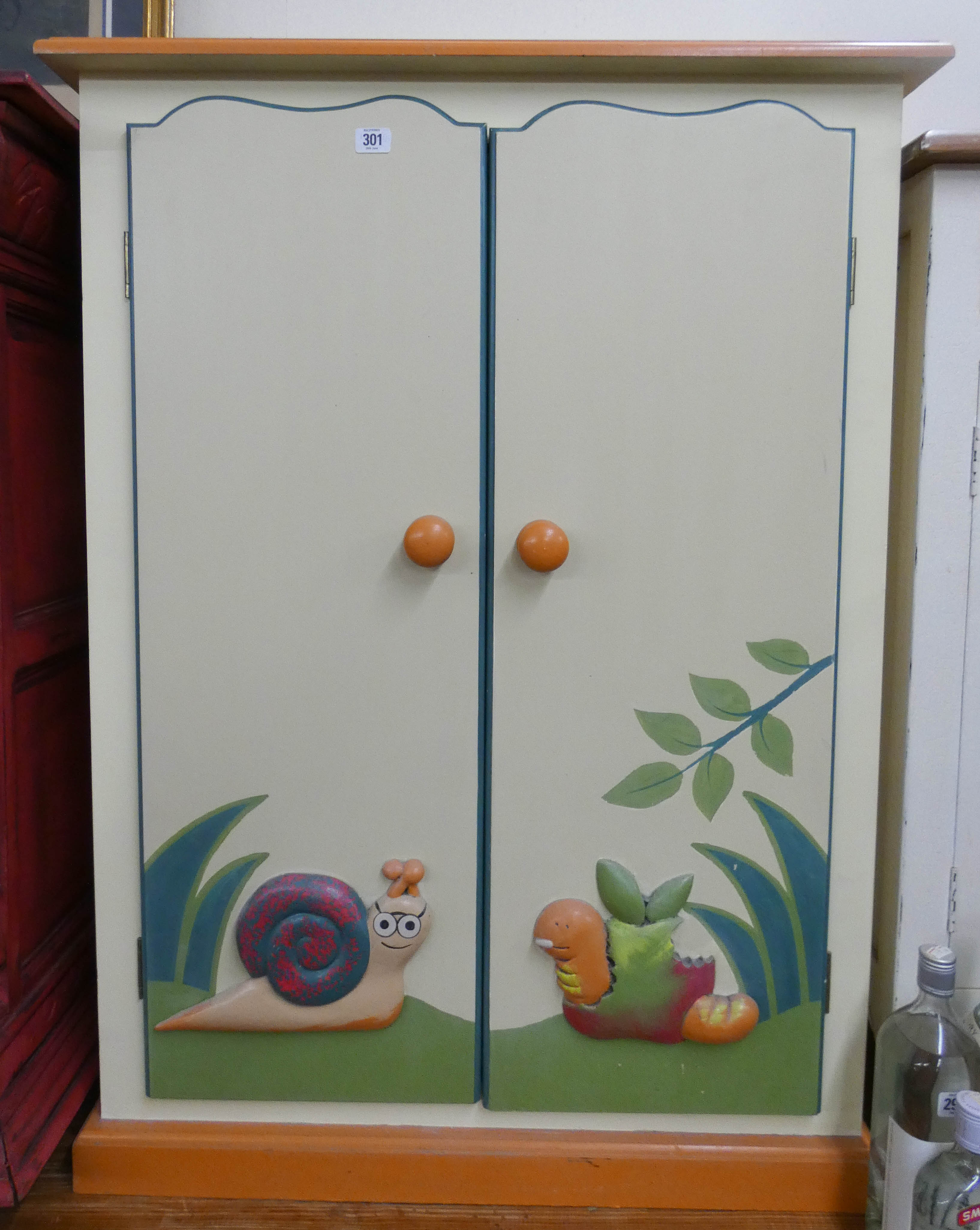 A child's painted dwarf wardrobe with relief moulded animals to the doors