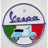 A circular cast iron wall hanging Vespa sign