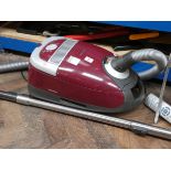 A red Miele cylinder vacuum cleaner in full working order