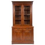 A late Victorian walnut bookcase on cupboard having a pair of glazed doors above two frieze drawers,