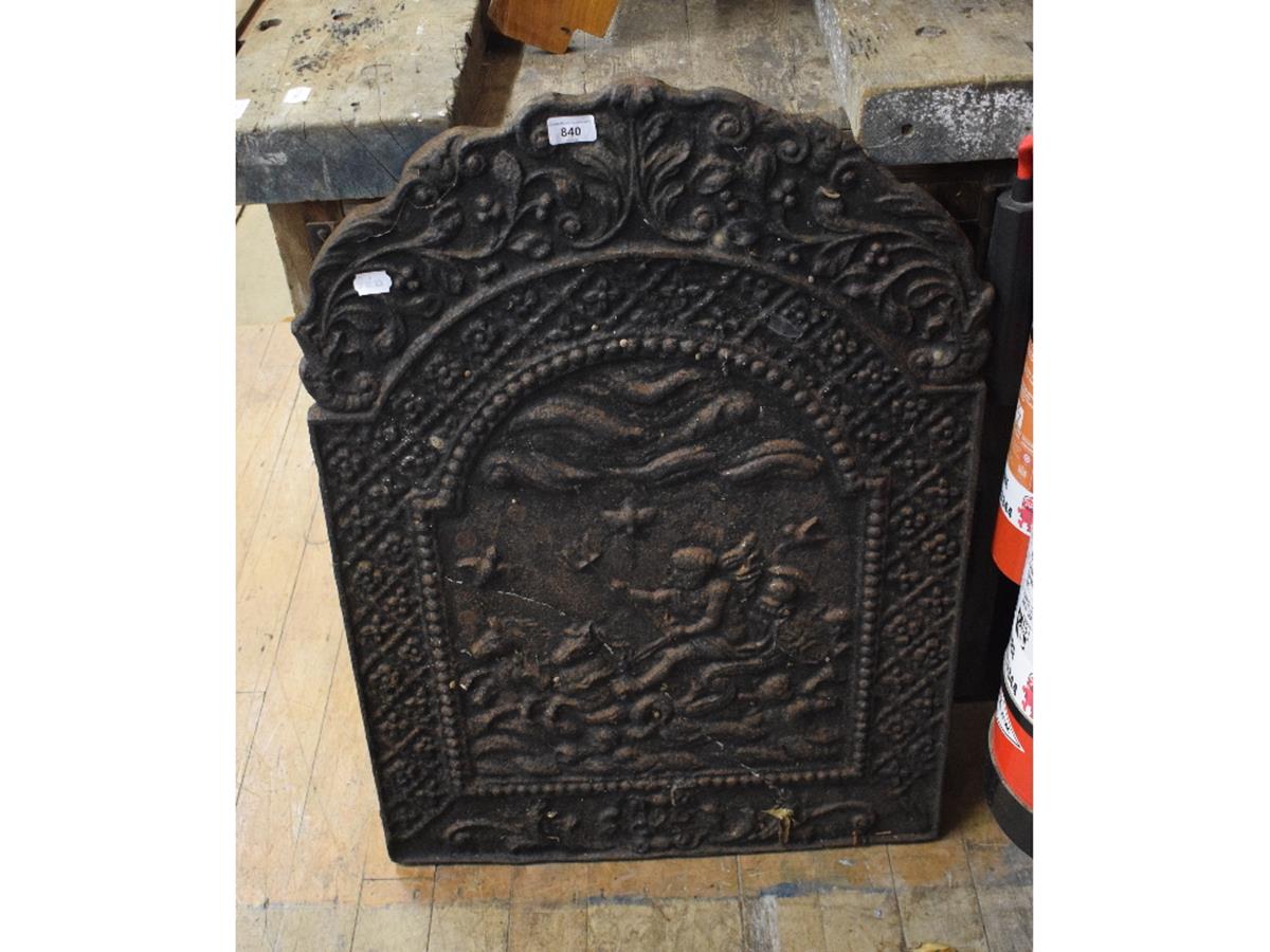 A cast iron fireback, decorated a chariot scene within an arched floral border, 60 cm wide