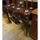 A George III style mahogany serving table, of shaped outline, having a lift up top above a frieze
