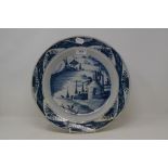 A 19th century Dutch Delft charger, decorated dwellings, slight restoration, 35.5 cm diameter