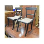 A set of four Anglo-Indian ebony sabre legged dining chairs, with cane seats (4)