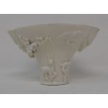 A Chinese Blanc de Chine porcelain libation cup, with applied animals and scrolling foliage,