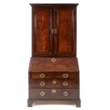 A George III mahogany bureau bookcase, the moulded and dentil cornice above a pair of panel doors,