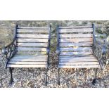 A pair of cast iron garden chairs, with wooden slat back and seats (2) Chairs are 62.5 cm wide