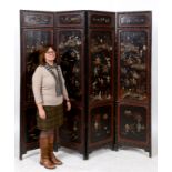 A Chinese lacquered four fold screen, inset soapstone, mother of pearl, and bone figures, fruit,