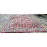 A large modern machine made carpet, decorated floral motifs on a red ground, within a multi