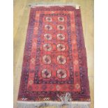 An Afghan style rug, with elephant ghul motifs on a red ground, 199 x 104 cm