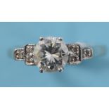 An 18ct white gold, platinum and diamond ring, the central modern brilliant cut stone flanked by