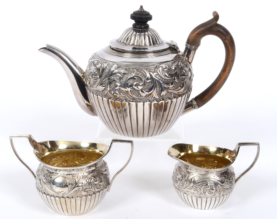 A Victorian silver three piece tea service, with scrolling foliage border embossed bird heads,