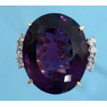 A large oval amethyst ring, the central stone flanked by four brilliant cut diamonds, in a yellow