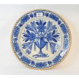 A 19th century Dutch Delft plate, decorated a vase of flowers in underglaze blue, 35 cm diameter