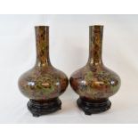A pair of cloisonné vases, decorated stylised flowers on a copper ground, 25 cm high, on carved