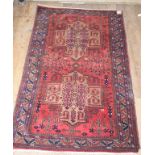 An Eastern rug, decorated geometric motifs on a red ground, within a multi border, 237 x 132 cm