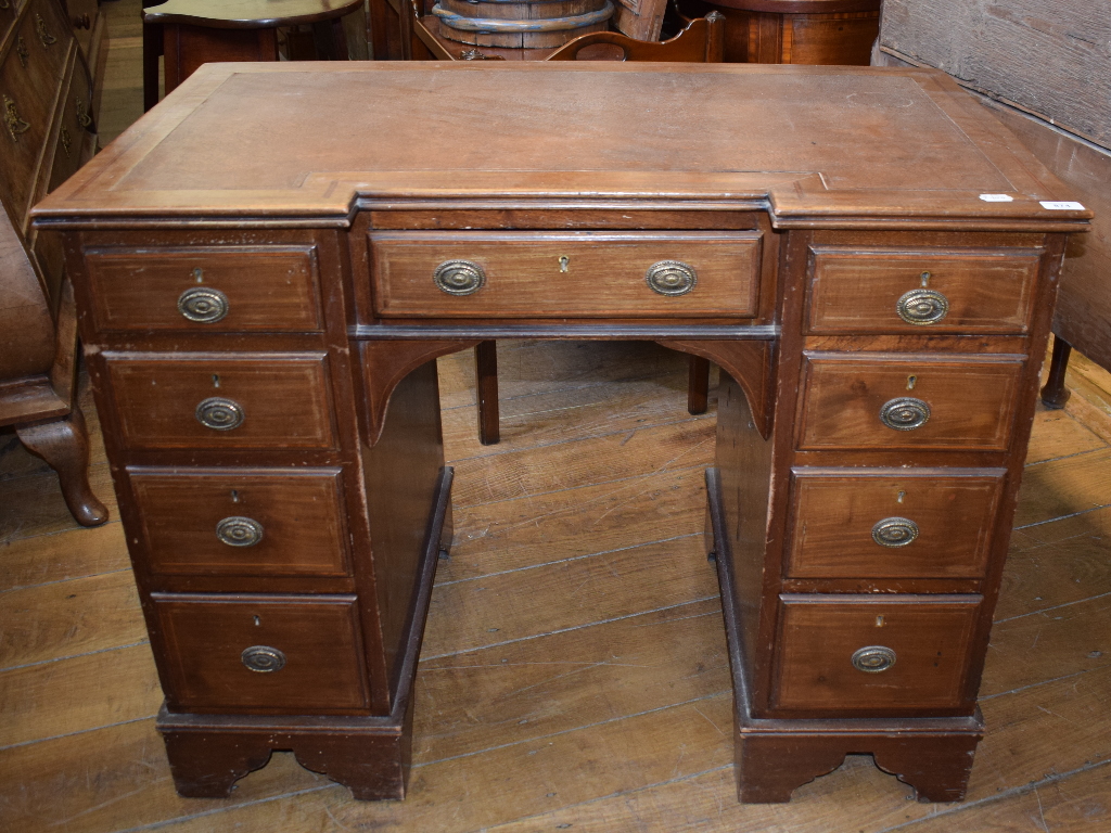 An Edwardian inlaid mahogany desk, of inverted breakfront form, the leatherette inset top above an