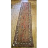 An Eastern runner, decorated motifs on a red ground, within a multi border, 430 x 92 cm