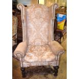 A large Colonial wing back armchair, on turned and carved legs and stretchers
