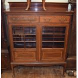 An Edwardian inlaid mahogany cabinet, having two frieze drawers above a pair of glazed doors, on