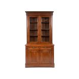 A late Victorian walnut bookcase on cupboard, having a pair of glazed doors above two frieze drawers