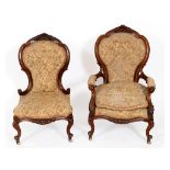 A pair of Victorian walnut his and hers button back armchairs, with carved decoration See