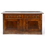 A George III oak dresser base, the top with canted corners above two frieze drawers and a pair of