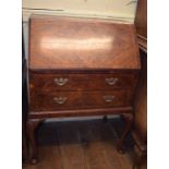 A George I style burr walnut bureau, on shell capped cabriole legs with pad feet, 74 cm wide