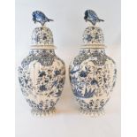 A pair of Dutch Delft vases and covers, with bird finials, and decorated birds, flowers and foliage,