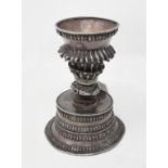 A Tibetan silver coloured metal ritual cup, on a spreading circular base, 10 cm high Some holes,