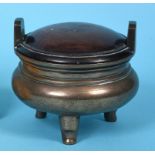 A Chinese bronze censer, of compressed circular form, with an associated wood cover and three