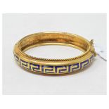 A Grecian revival yellow coloured metal bangle, with blue enamel Greek key decoration, losses to