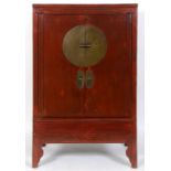 A Chinese red stained marriage cabinet, having a pair of brass mounted doors opening to reveal a