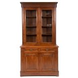 A late Victorian walnut bookcase on cupboard, having a pair of glazed doors above two frieze