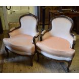 A pair of Continental walnut armchairs, with carved decoration and beige upholstery