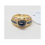 An 18ct gold, sapphire and diamond ring, the central cabochon sapphire flanked by princess cut