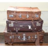 A leather suitcase, with straps, and chrome mounts, 77 cm wide, and two others similar, 66 and 60 cm