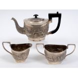 An Indian silver coloured metal three piece tea service, embossed a tiger hunt and farming scenes,