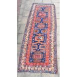 A Caucasian carpet, with geometric motifs on a blue ground, within a multi border, 330 x 120 cm