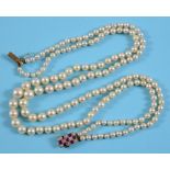 A cultured pearl two strand necklace, with a yellow coloured metal, diamond and garnet clasp See