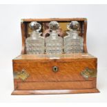 A late Victorian/Edwardian oak tantalus, with plated mounts, and three decanters and stoppers, 34 cm