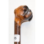 A walking stick, the wooden handle carved with a boxer dog head, lacks eyes and ears