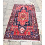 A Persian carpet, the central medallion on a red ground, 273 x 152 cm