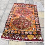 An Eastern rug, decorated medallions on an orange ground, within a multi border, 200 x 115 cm